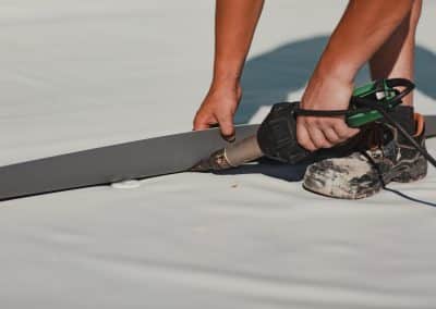 Worker welding pvc roof membrane by heater with welder machine