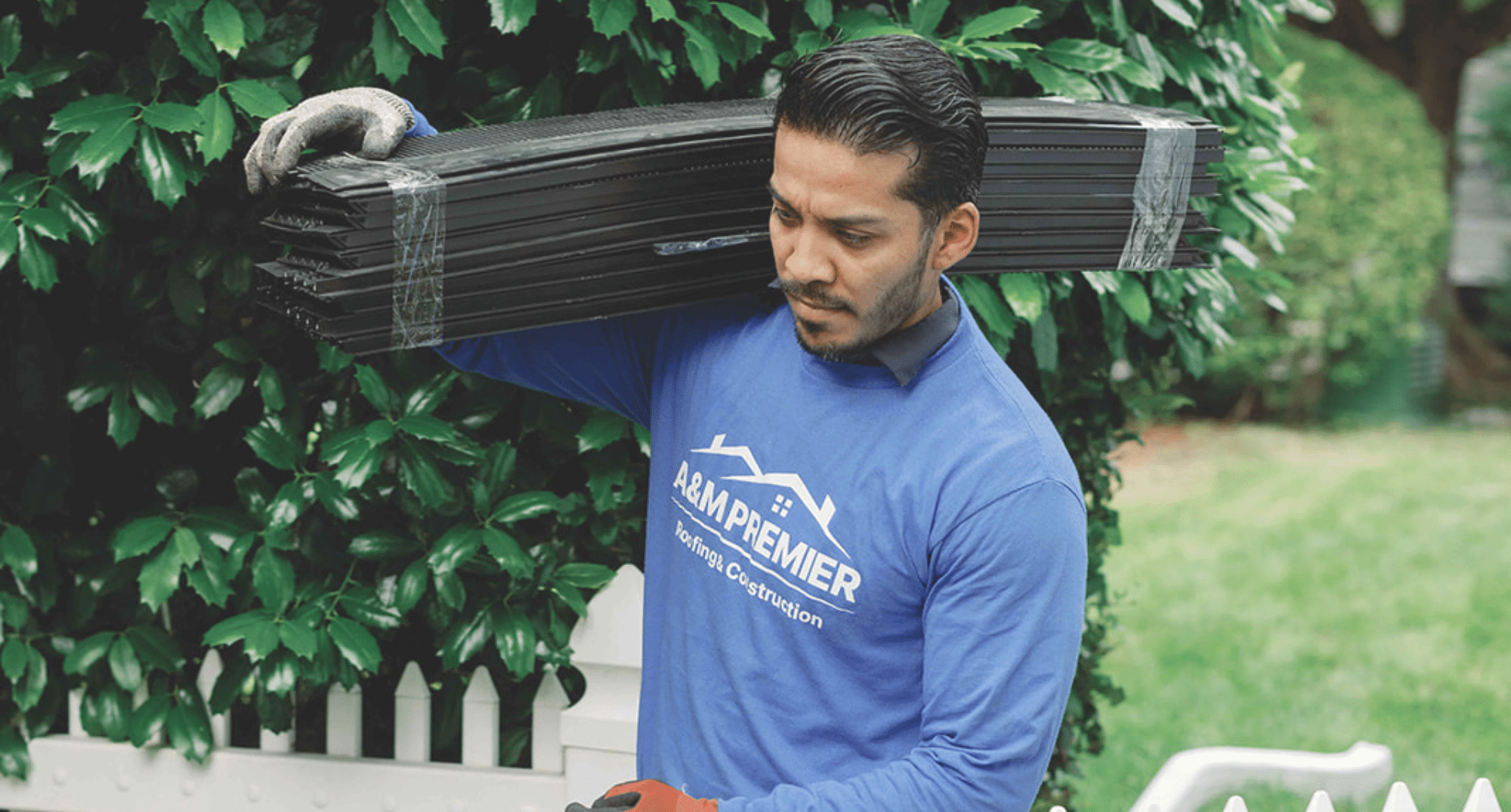 Man moving roofing material wearing a A&M Premier shirt